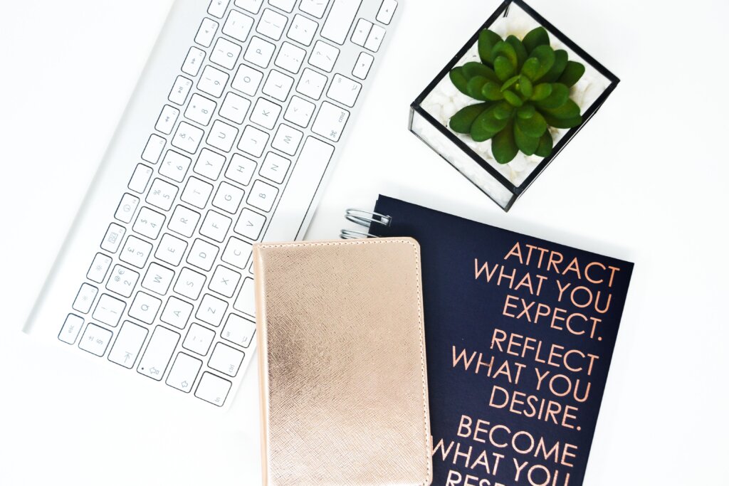 Keyboard with navy notebook, gold notebook, and green succulent