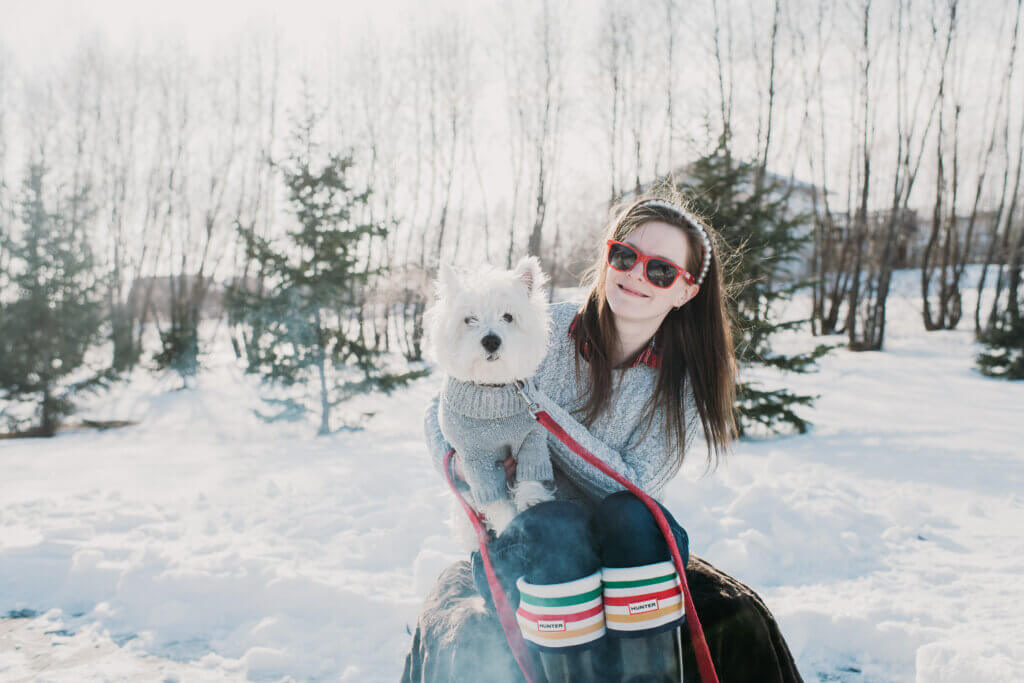 Girl with dog in sweater on lap in the snow