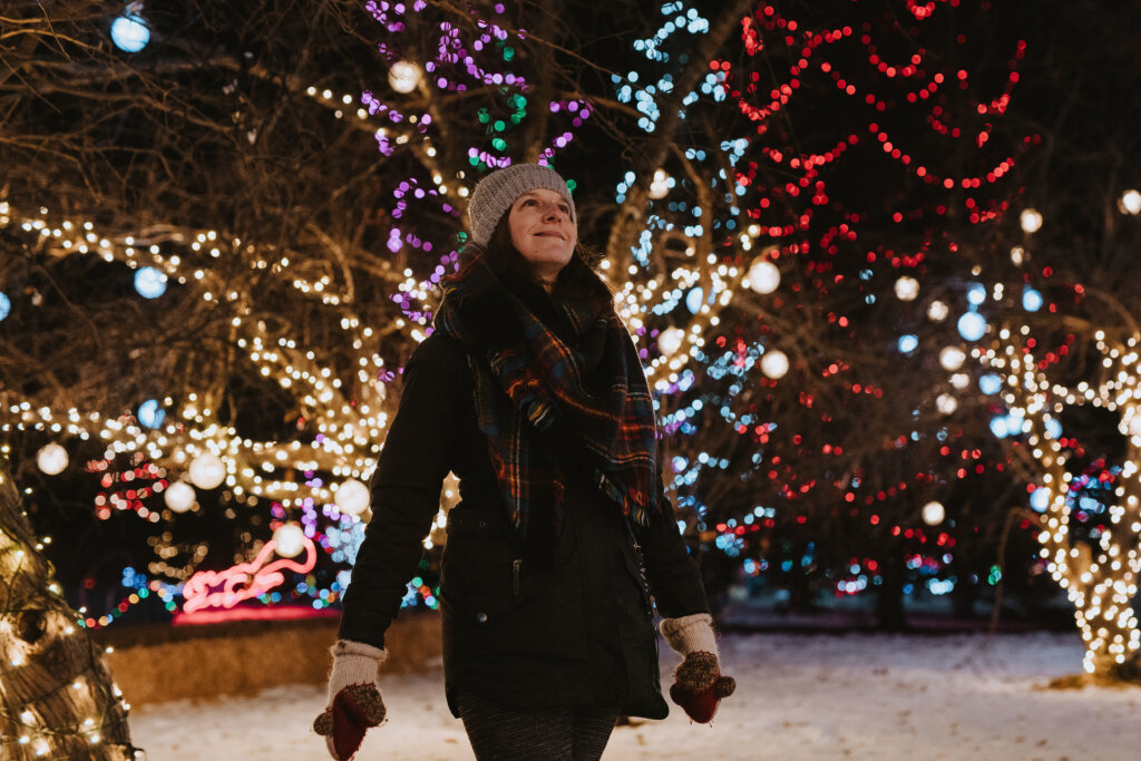 Woman walking through Christmas lights in the snow
