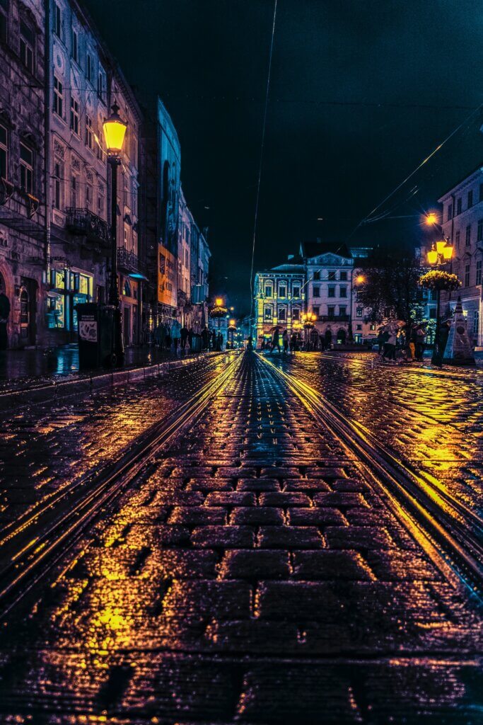 dark high street at night with lights reflecting on pavement