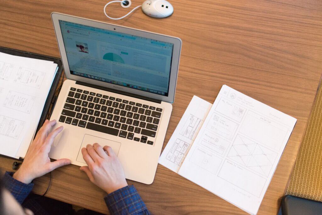 Person typing on laptop with notebooks beside them